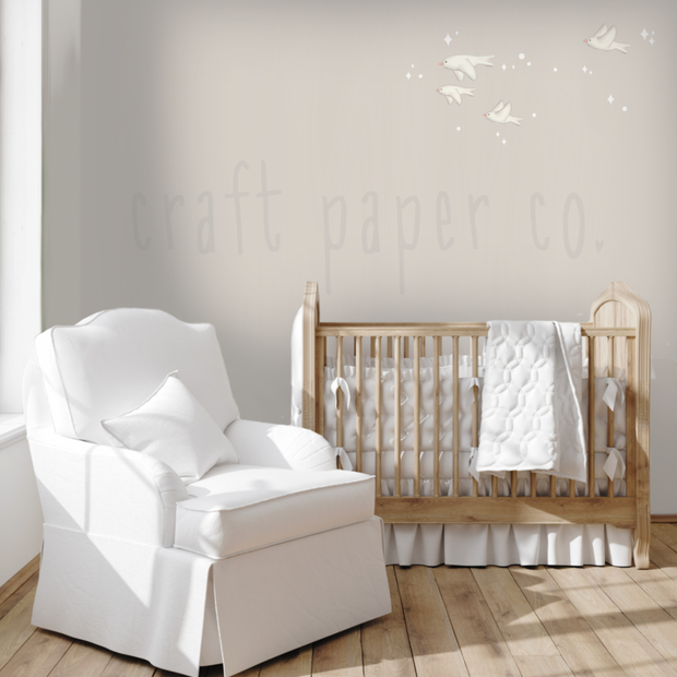 Minik Kuşlar Duvar Sticker; beyaz karyola ve koltuğun üstünde duvarda uçan beyaz kuşlar | Craft Paper Co