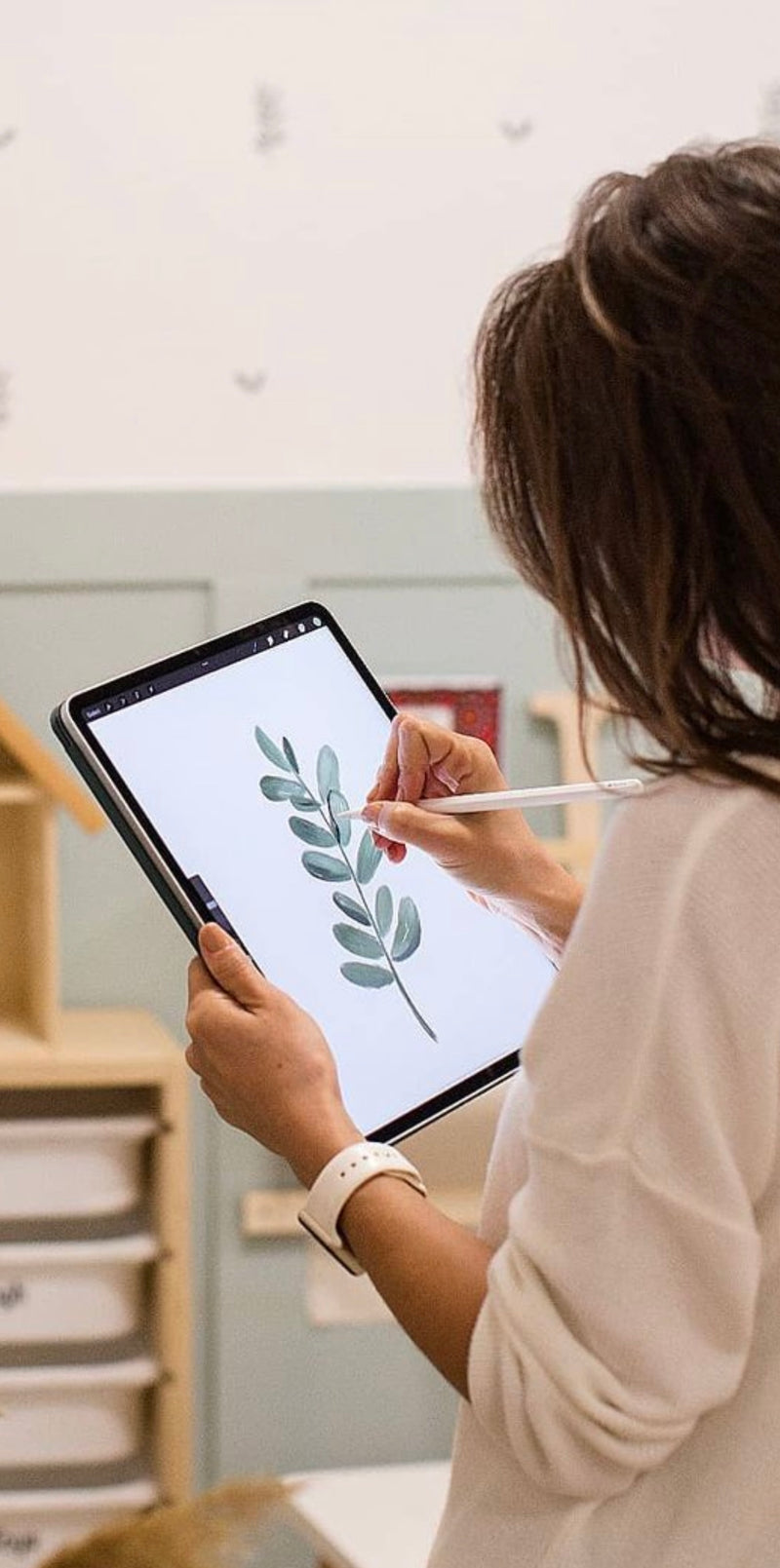 Tasarımcı Nihan Minareci tablette okaliptüs dalı çiziyor; el çizimi çocuk odası duvar kağıdı tasarım süreci